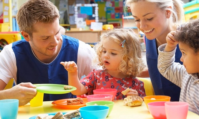 Monitores de comedor escolar atendiendo a niños durante la comida