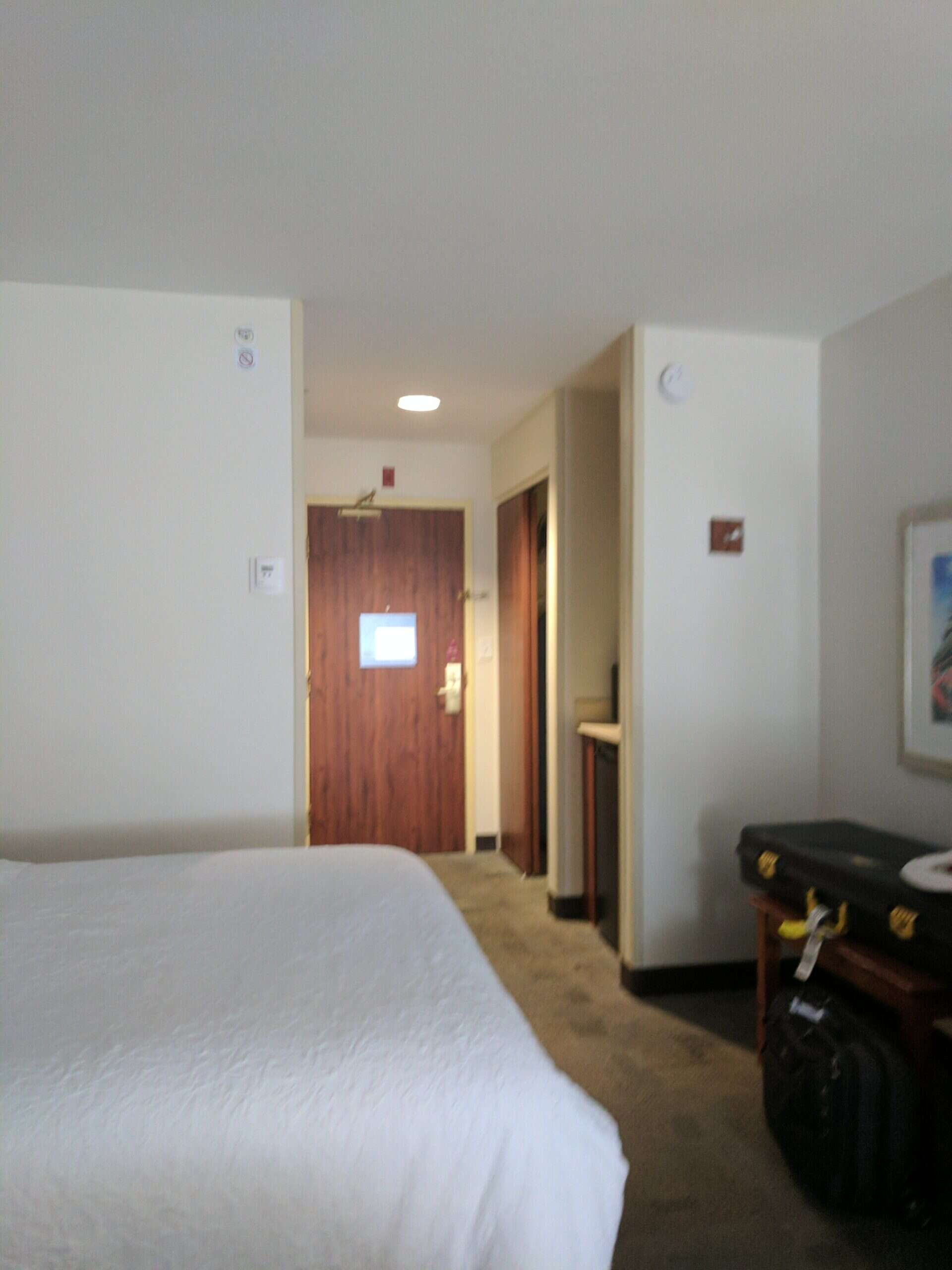 Cama de hotel recién hecha junto a un portamaletas con equipaje