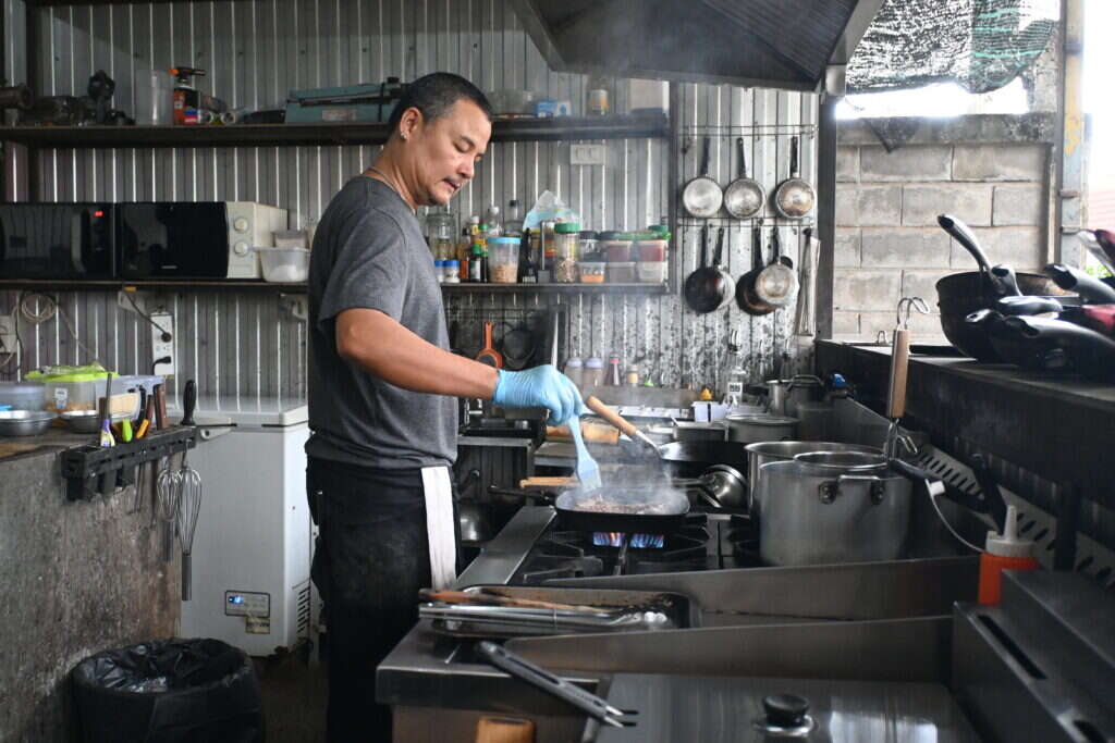 Cocinero con guante desechable salteando en un fuego de una cocina profesional