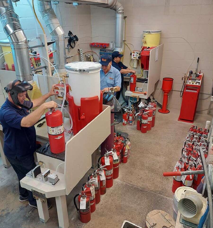 Técnicos revisando y recargando extintores en un taller especializado