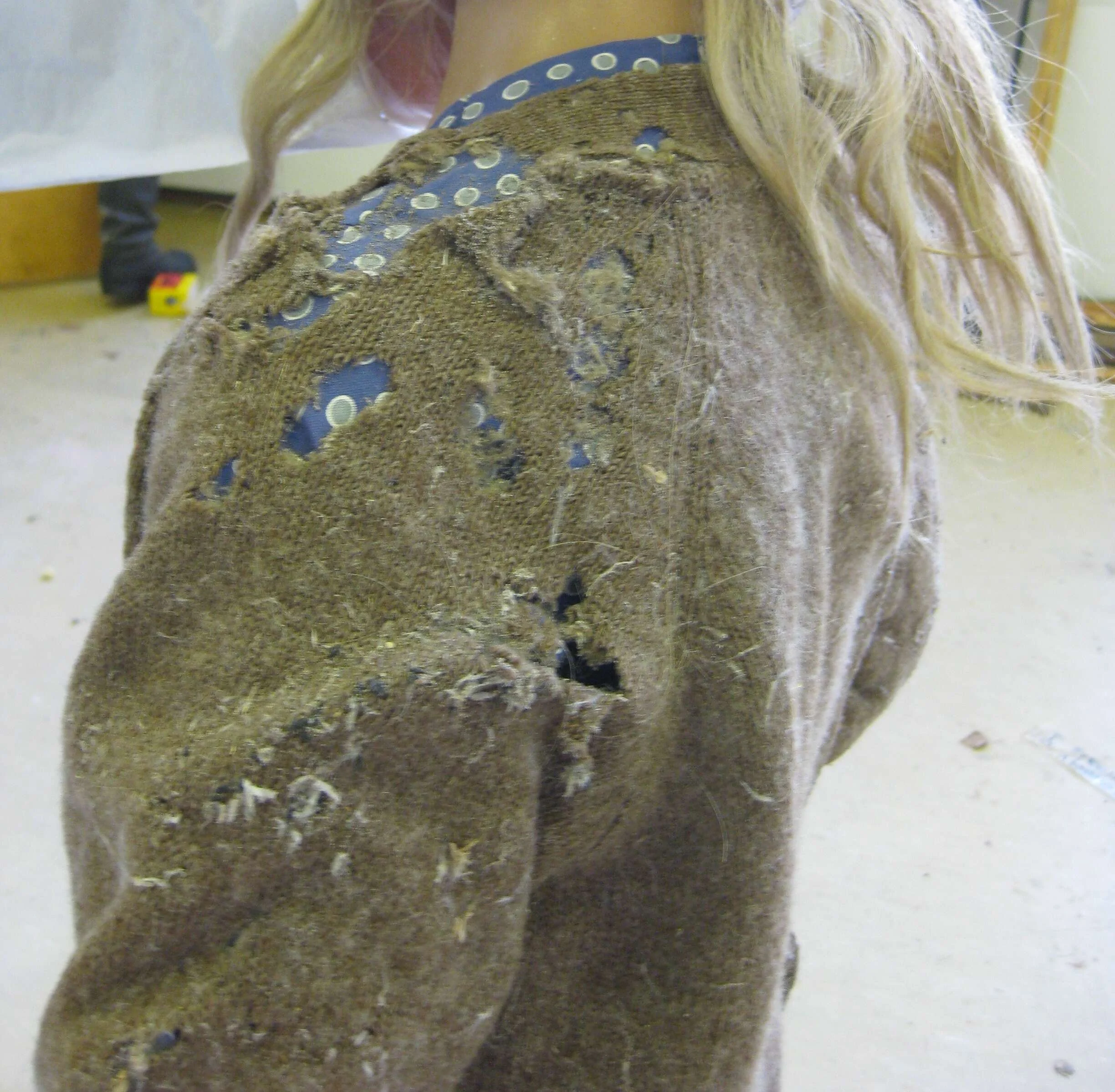 Chaqueta de lana con la manga y el hombro deshechos por la larva de la polilla de la ropa