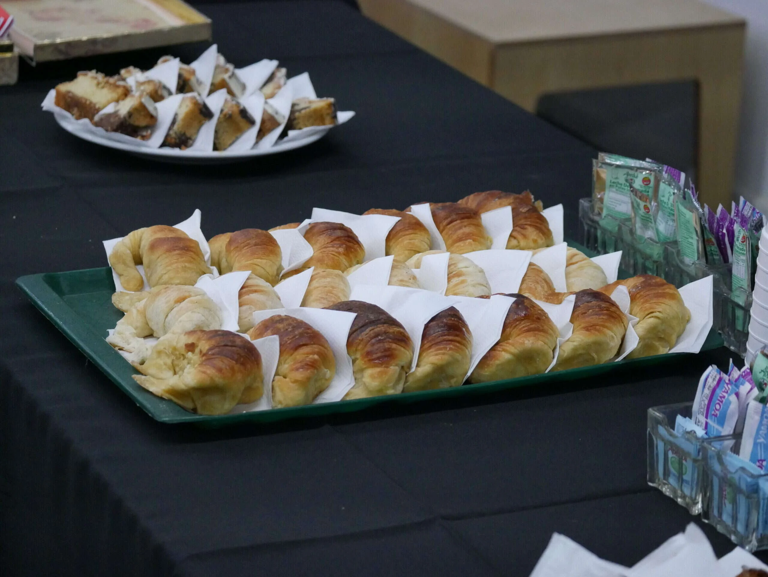 Bandejas de bollería montadas sobre mesa vestida en un servicio de catering