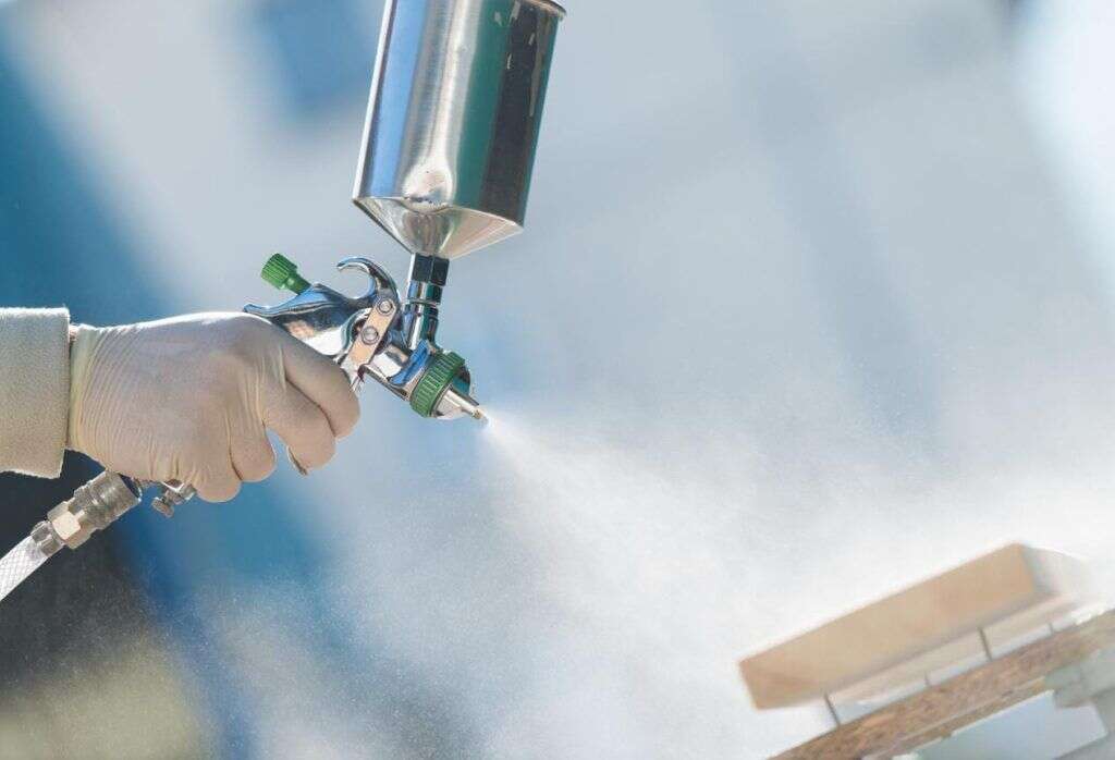 Técnico aplicando tratamiento ignífugo con pistola de spray sobre un tablero de madera