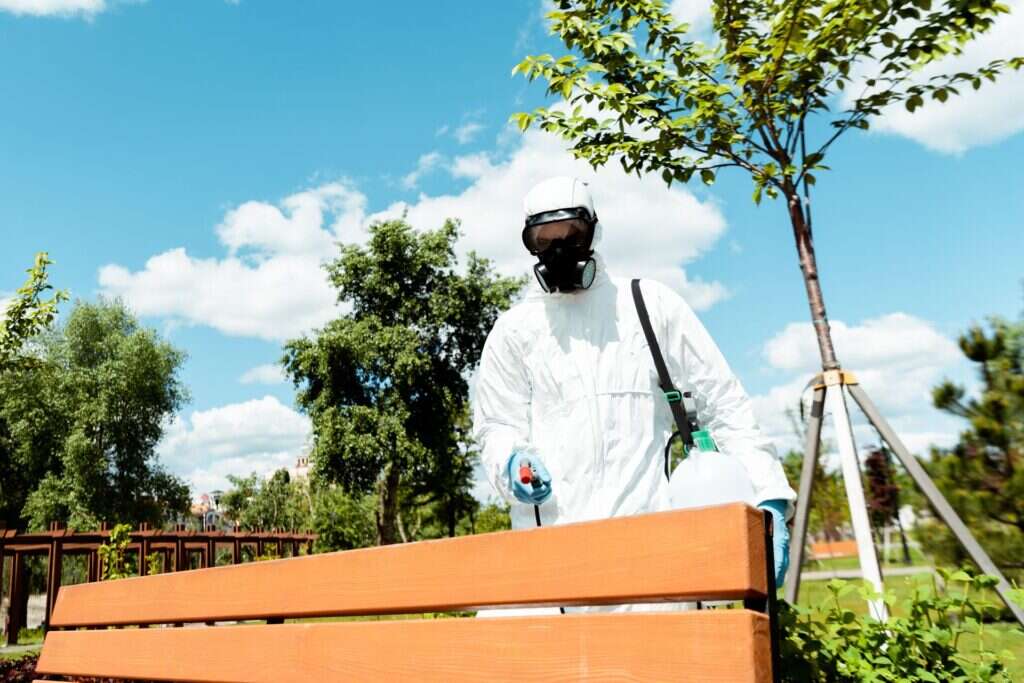 Técnico de Abansol aplicando tratamiento en una zona ajardinada con mobiliario de madera