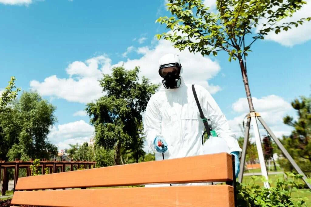 Técnico de Abansol aplicando tratamiento en una zona ajardinada con mobiliario de madera