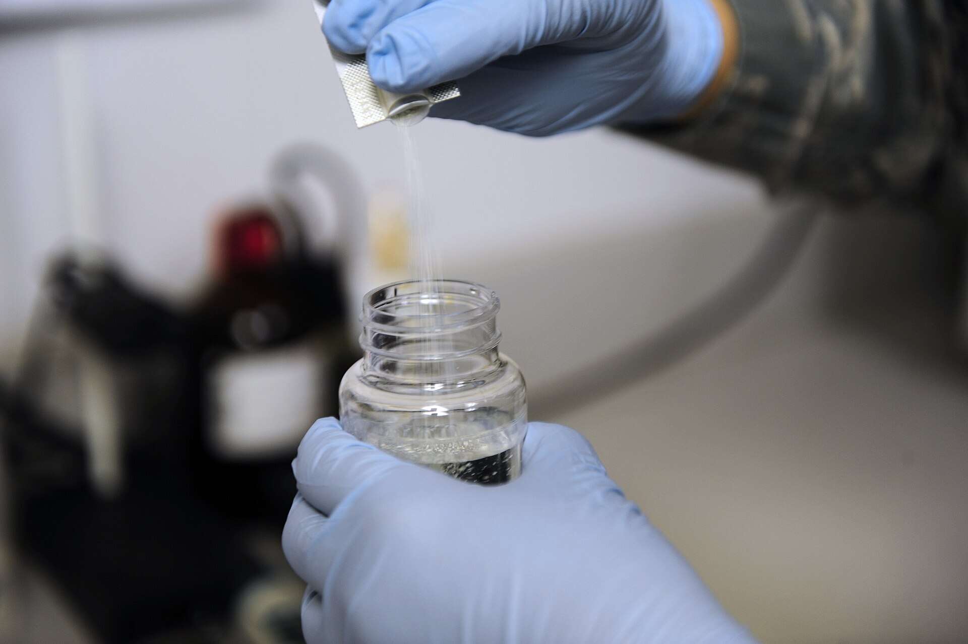 Técnico con guantes preparando una muestra de agua para su análisis