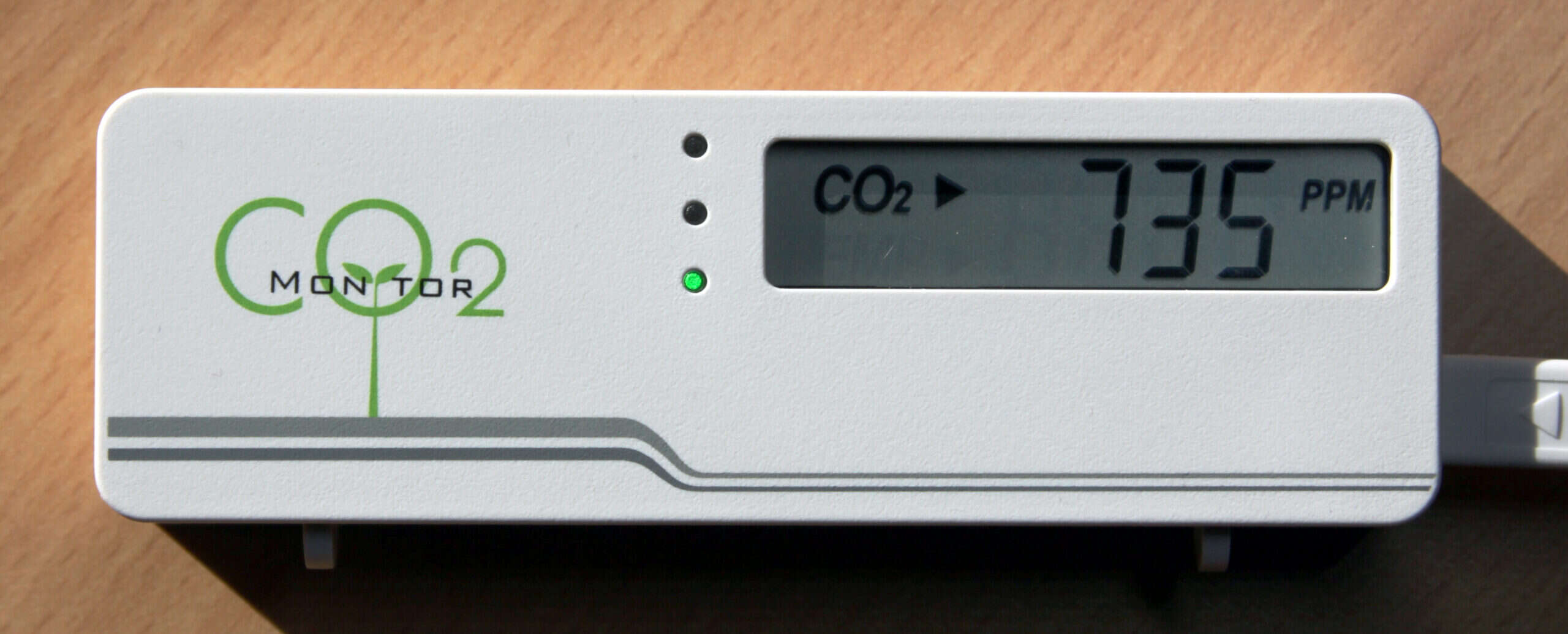 Medidor de dióxido de carbono marcando 735 ppm sobre una mesa