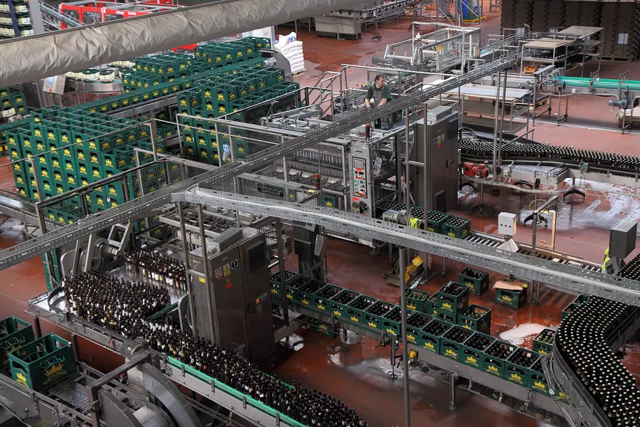 Botellas avanzando por la línea de llenado de una planta de bebidas